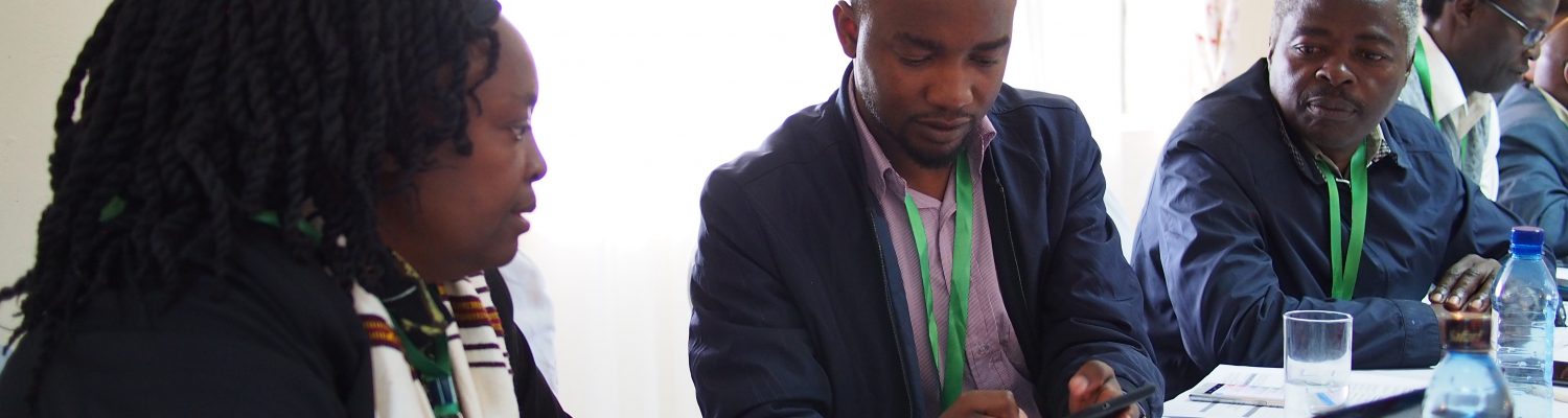 Dr Lusike Wasilwa, Director of Crop Systems, KALRO and Amos Tabalia, ACRE Africa, downloading the Telegram app and signing up to the PRISE pest forecasts.